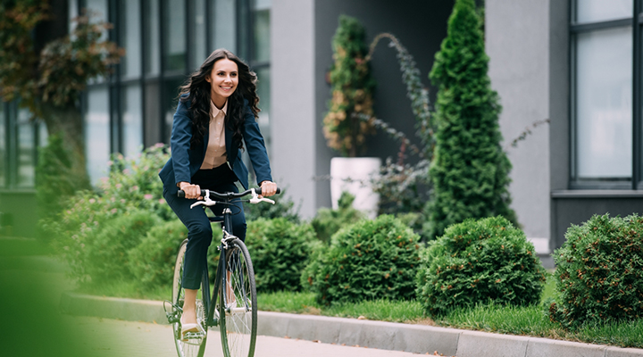 a young woman in business attire riding her bike outside